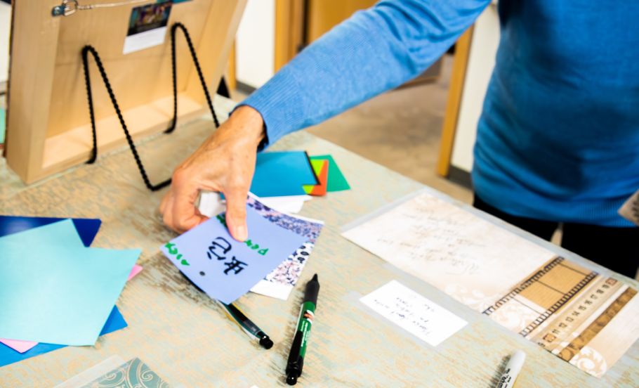 Person in a blue long-sleeve shirt is working with paper at a table.