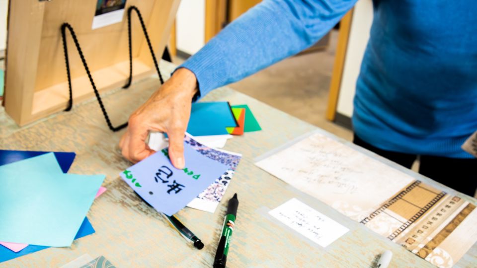 Person in a blue long-sleeve shirt is working with paper at a table.
